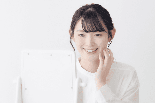 鏡を見て微笑む女性