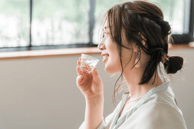 窓際でお酒を飲む女性