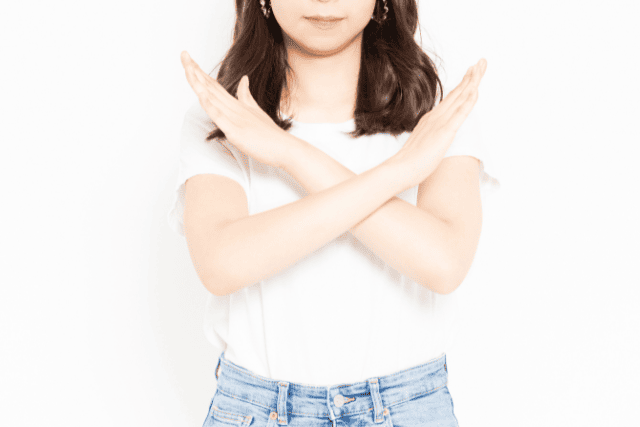 身体の前でバツを作る女性